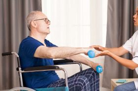 Disabled old man during physiotherapy talking with doctor about his pain. Disabled handicapped old person with social worker in recovery support therapy physiotherapy healthcare system nursing retirement home